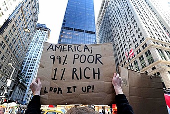 一名示威者举着一个牌子，上面写着“美国;99%的穷人，1%的富人。查一查!”